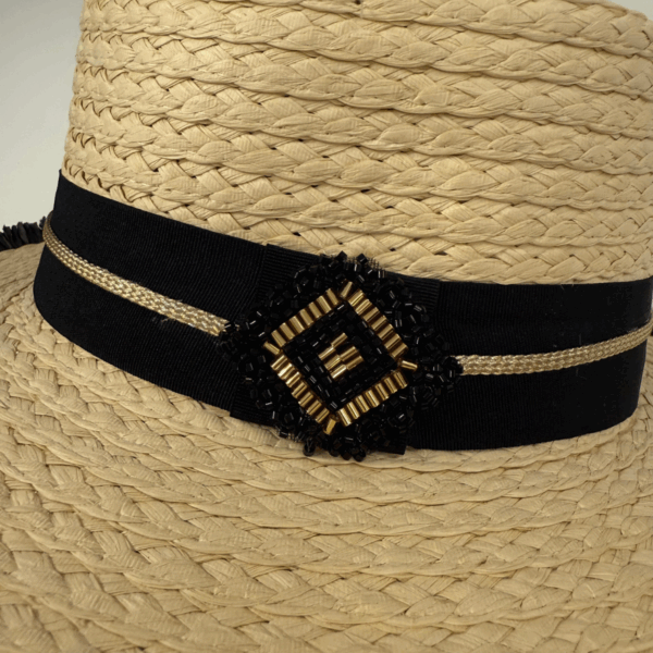 Paperstraw hat with black ribbon and gold embellishment close up